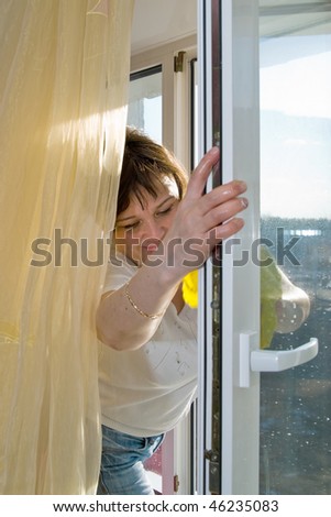 A woman washes a window in a house