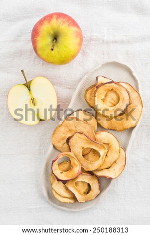 Dried apple slices in a handmade bowl and fresh apples
