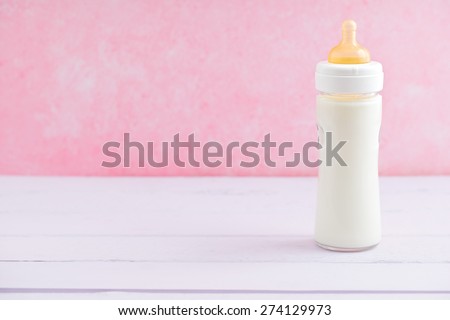 Baby milk bottle on pink table with neagtive space