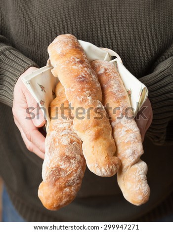 Man holding three rustic artisan French baguettes in basket
