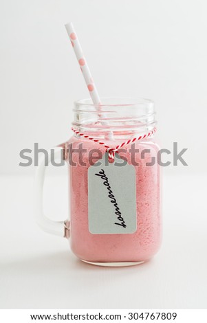 Healthy pink smoothie with berries and yogurt in a glass with handwritten homemade label