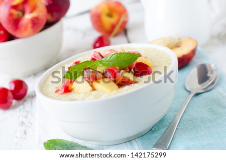 Milk porridge with peaches and cherries. Selective focus
