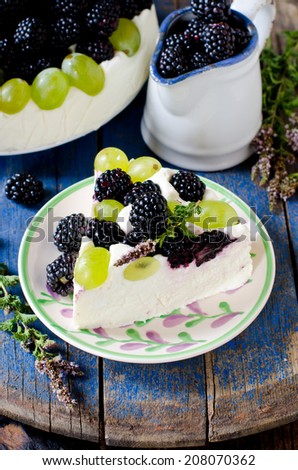 Cheesecake with blackberries and grapes on a wooden table old