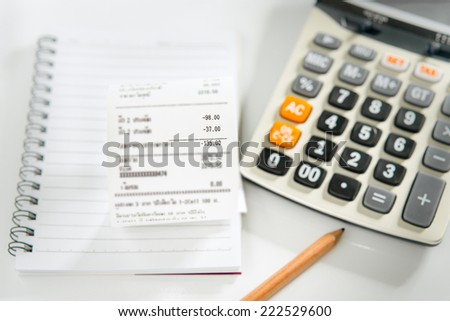 Grocery shopping list on notebook with calculator and pencil - money account management concept