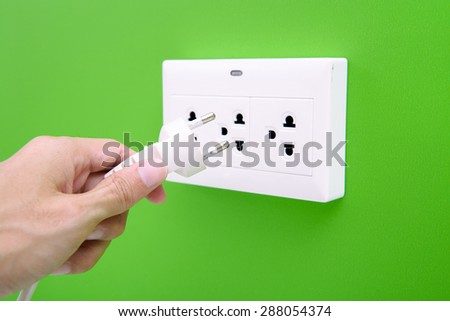 Hand hold electric power plug and inserting into power wall socket