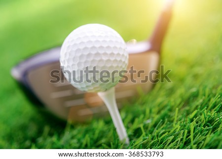 Golf club and ball on green grass