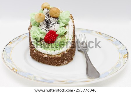 Cake with mushrooms and leaves from cream on a plate with dessert fork..