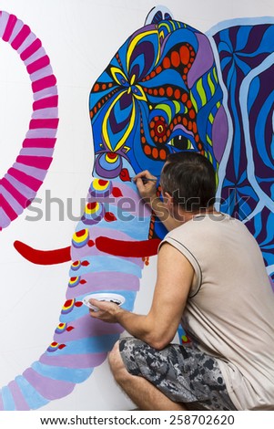 Painter paints with acrylic paints picture on the wall.