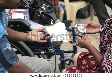 HYDERABAD,INDIA-FEBRUARY 28:Nurse checking Blood sugar level of a man in a medical camp during happy roads program(vehicular Traffic stopped)  in necklace road on February 28,2015 in Hyderabad,India.