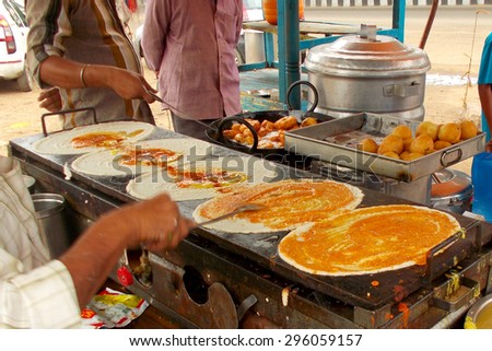 HYDERABAD,INDIA-JUNE 18:Street vendor make dosa,popular  breakfast on a mobile cart on June 18,2015 in Hyderabad,India.A common scene in urban india as people cant afford high cost in restaurants.