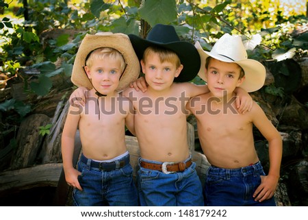 Three brothers, shirtless and wearing cowboy hats and jeans