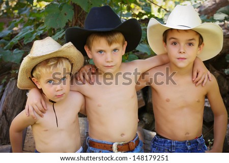Three brothers, shirtless and wearing cowboy hats and jeans