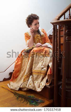 A young woman in historical clothing in the stairway of an 18th century mansion
