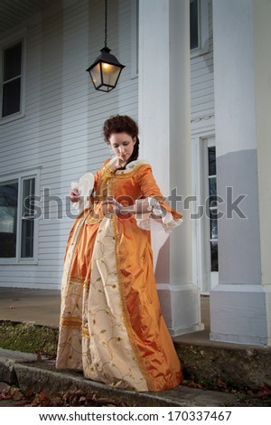 A young woman in historical clothing in front of 18th century mansion