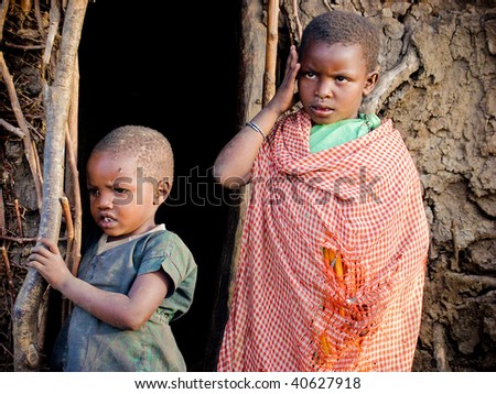 MASAI MARA, KENYA  - JANUARY 6: Small children standing in the door of the Masai tribe village house on January 6, 2004 in Masai Mara, Kenya. Social issue of poor African countries.