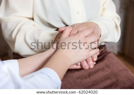 Helping hands: the nurse holds hands of the elderly female
