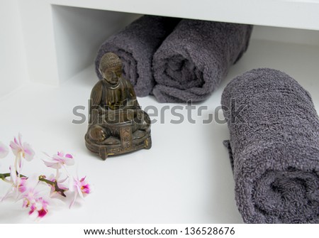 a still life with buddha figure, orchid blossom and towel