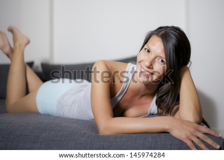 woman lay down on sofa and smiles
