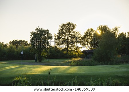 sun rays on the green of a golf course at sunset