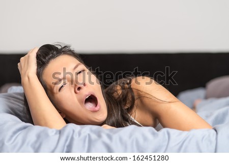 Tired young woman yawning as she spends a lazy day relaxing at home