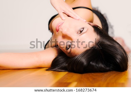 Beautiful appealing young woman lying on her back in seductive lingerie looking back at the camera with a serious wide eyed expression