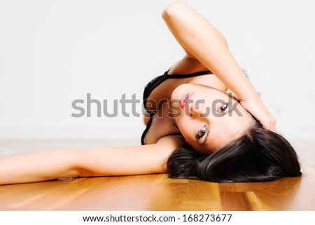 Beautiful appealing young woman lying on her back in seductive lingerie looking back at the camera with a serious wide eyed expression