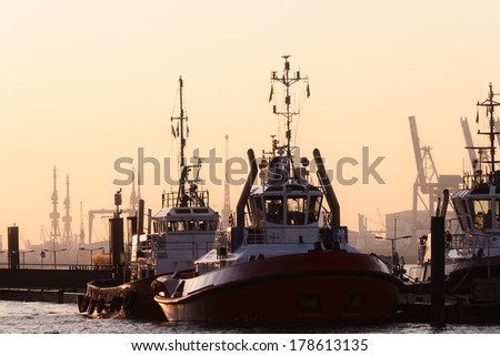 Two tugboats moored in a harbor at sunset with their reinforced bows for pushing or towing ships at sea to maneuver them and aid in navigation