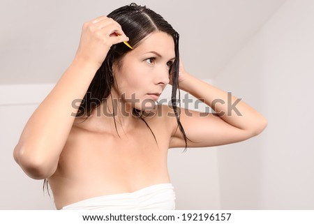 Young woman carefully combing lice out of her hair with a very fine toothed lice comb in an effort to control the infestation of tiny wingless bloodsucking insects