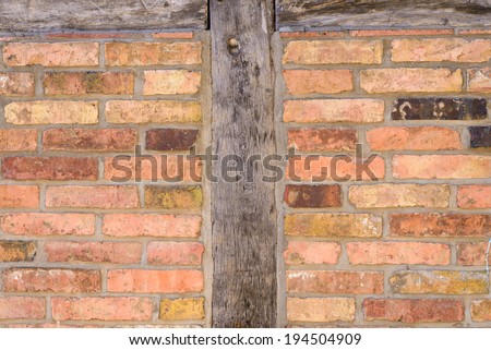 Old brick wall background texture with wooden uprights on either side constructed of old thin clay face bricks
