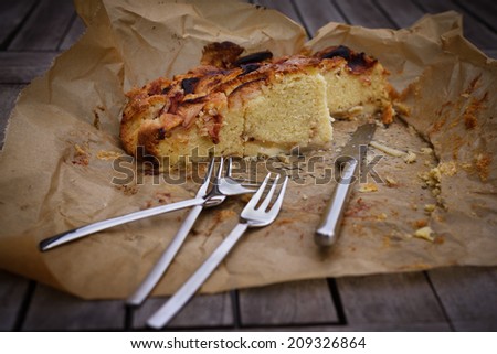 Crusty and delicious apple pie on paper with knife and fork place on a table, side view