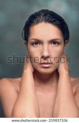 Close Up Portrait of Serious Woman with Minimal Make Up with Hands Behind Neck in Studio