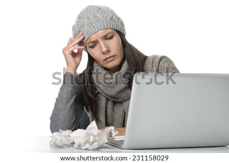 Young businesswoman with a seasonal cold and flu sitting behind her computer holding her head, isolated on white