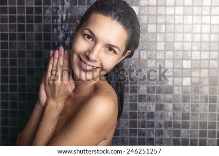 Attractive woman washing her hair in the shower rinsing it off under the spray of water with her head tilted back looking away in a hair care, beauty and hygiene concept