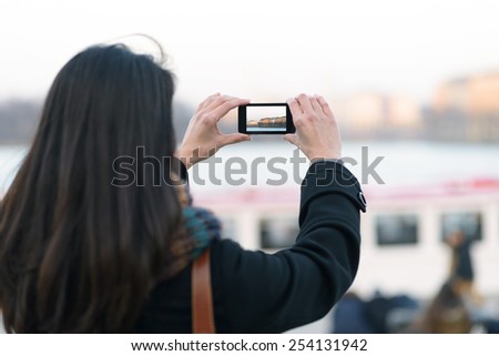 Close up Rear of a Long Hair Woman Taking Outdoor View using her Modern Mobile Phone