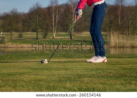 Close up low angle view of the lower body of a woman teeing off at a golf course with a driver