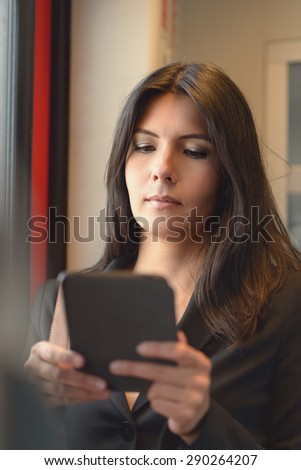 A portrait of attractive brunette woman using tablet in train, while commuting from work