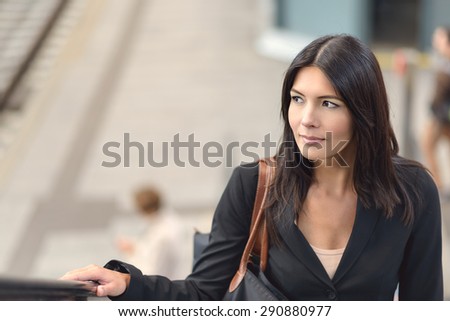 Attractive brunette businesswoman riding the escalator in public space