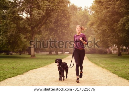 Full length Shot of a Healthy Young Woman Jogging in the Park with her Black Pet Dog