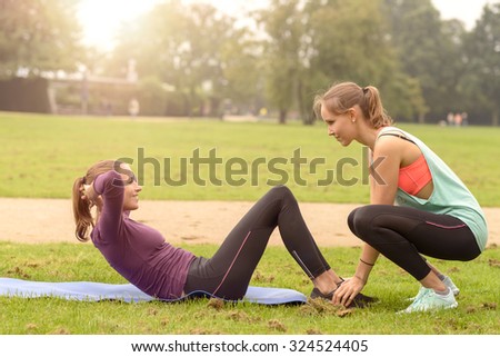 Happy Athletic Woman Smiling at her friend While Doing Curl Up Exercise at the Park