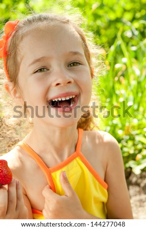 Smile little girl in summer day with strawberries