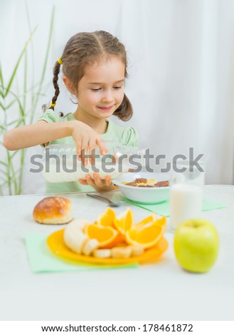 Cute little girl eating muesli with milk and fresh fruits