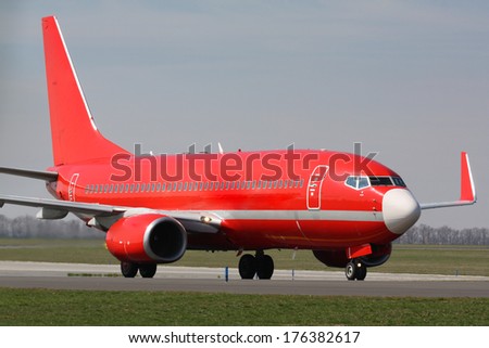 Red plane taxiing after landing to terminal