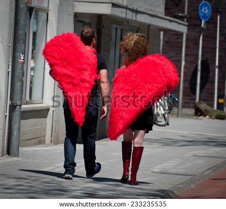 EINDHOVEN, NETHERLANDS - JUNE 8, 2013: An adult couple with half-heart shaped costumes walking in the streets of Eindhoven.