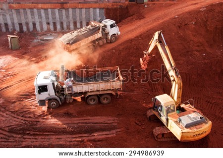 BRASILIA, BRAZIL - JUNE 6, 2015: Excavator loading dumper truck tipper in construction site of a new commercial building.
