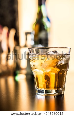 Glass of scotch whiskey and ice on the background of the bar