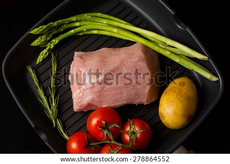 Meat with rosemary, potatoes, asparagus and cherry tomatoes cooking in a frying pan