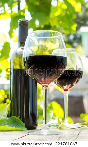 Red wine bottle and wine glass on wooden table