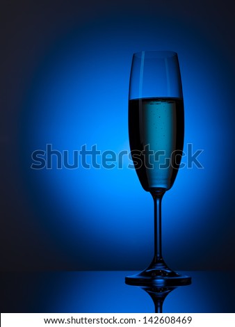 Champagne flute over blue gradient on black reflective background