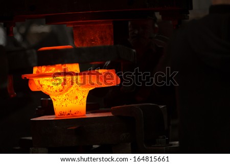 a glowing iron ingot into the press