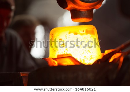 a glowing iron ingot into the press